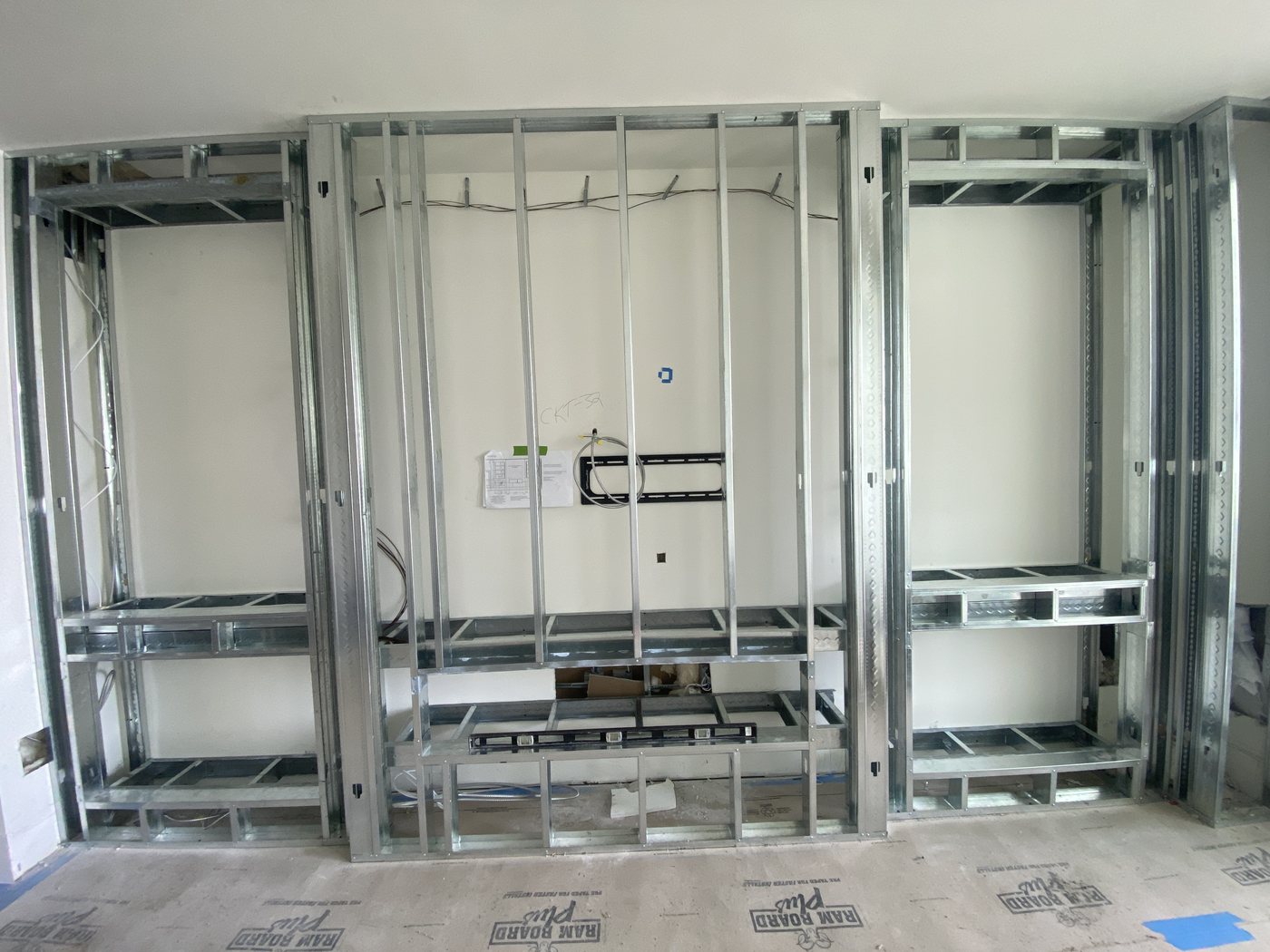 Metal stud framing built out for a media wall with niches and shelf blocking