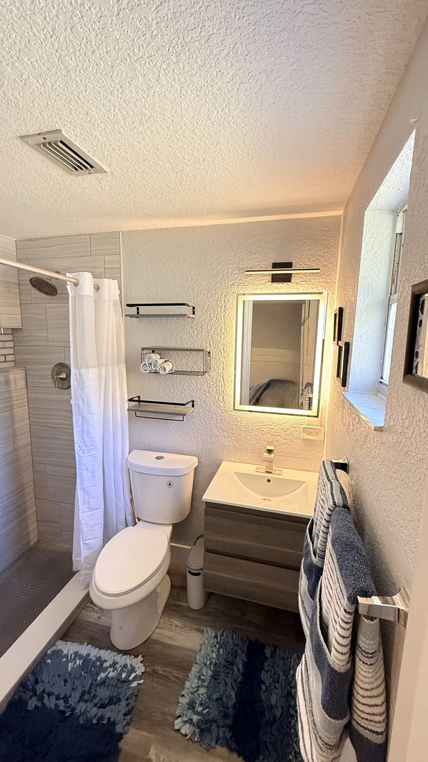 Guest bathroom remodel with backlit mirror and tiled shower