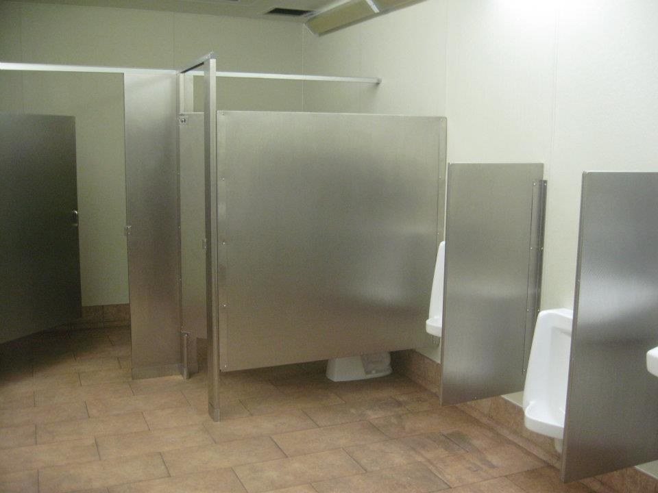 Finished commercial restroom with stainless partitions and code-compliant fixtures