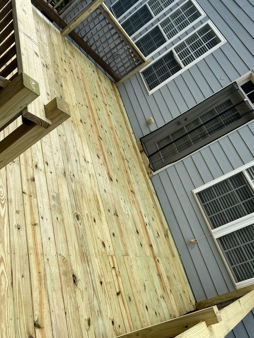 Large pressure-treated deck with railings and stairs, completed