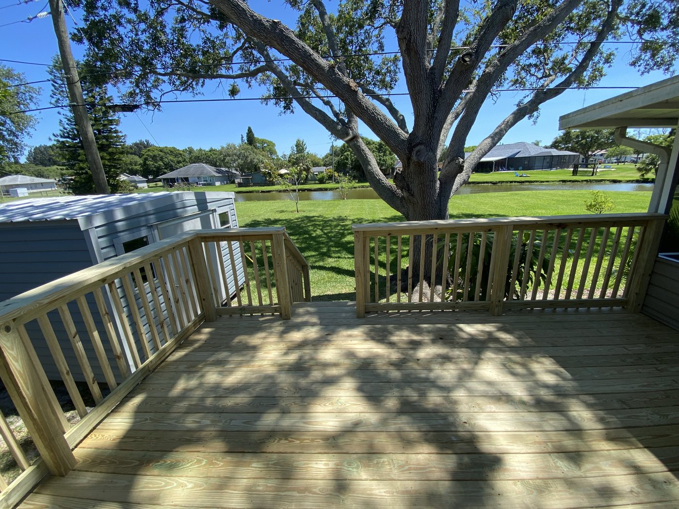Finished pressure-treated deck with railing under a live oak