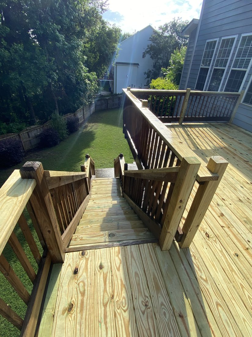 Completed pressure-treated deck with railings and stairs down to the yard
